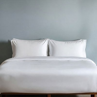 White Bed with Pillows Against Gray Wall