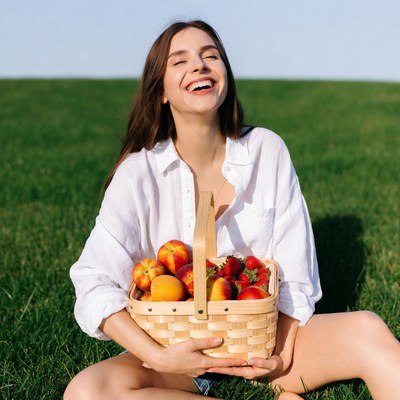 Woman holding basket of peaches strawberries
