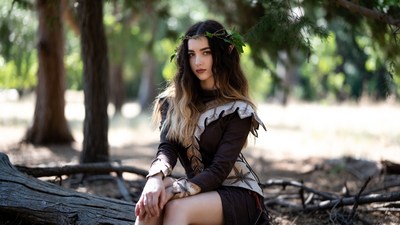 Woman in elf costume sitting on log