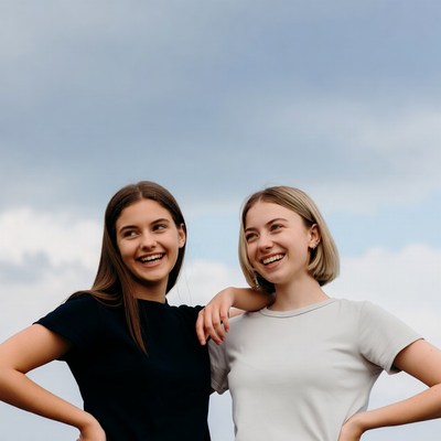 Two smiling girls embracing outdoors