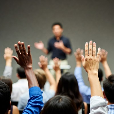 Diverse audience raising hands at seminar