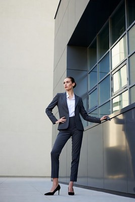 Woman in gray suit leaning on building