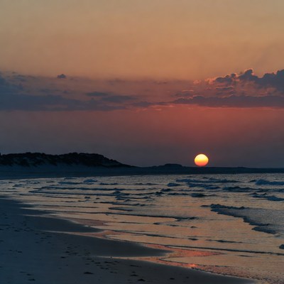 Sunset over beach with footprints