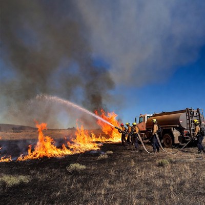Firefighters battling wildfire with truck