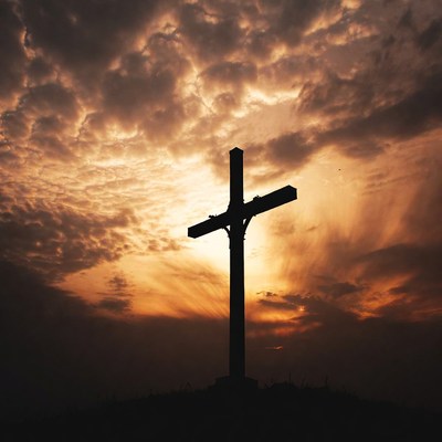 Silhouette cross against sunset clouds