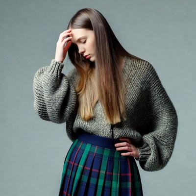 Young woman touching forehead in sweater skirt