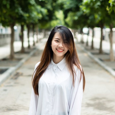 Asian woman smiling in tree-lined avenue