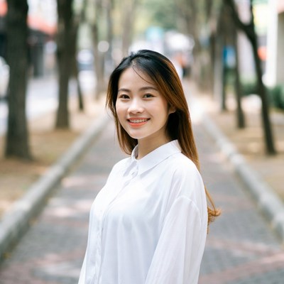 Asian woman smiling in tree-lined street