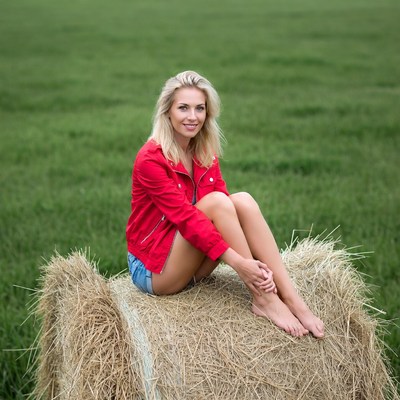 Blonde woman sitting on hay bale