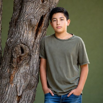 Latino boy leaning against tree