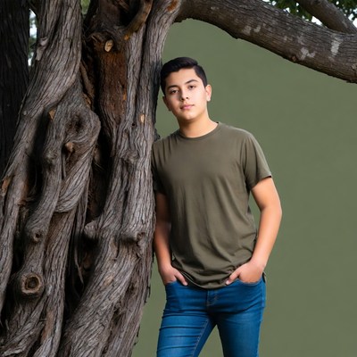Latino teen leaning against tree
