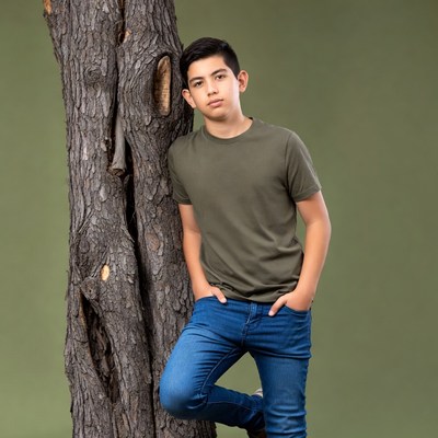 Latino boy leaning against tree