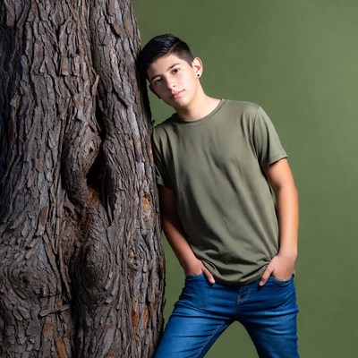 Latino boy leaning against tree
