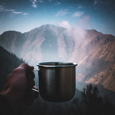 Hand holding mug with mountains