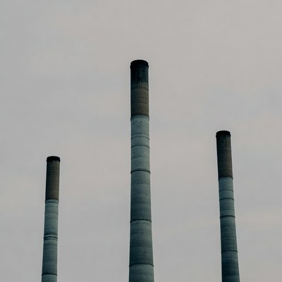 Three tall smokestacks against cloudy sky