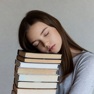Girl sleeping on stack of books