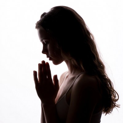 Woman praying in silhouette profile