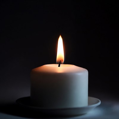 White candle burning on saucer