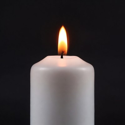 White Candle Burning on Black Background