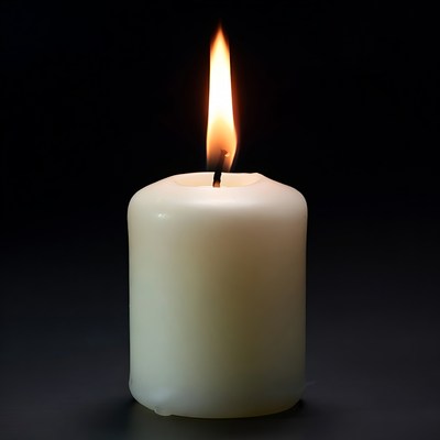 Burning white candle on black background