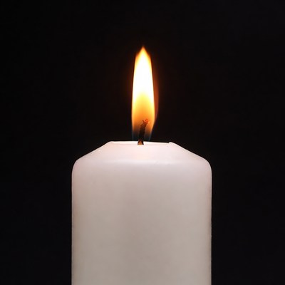 White candle burning on black background