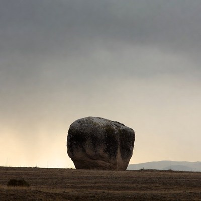 Large mossy boulder in stormy field