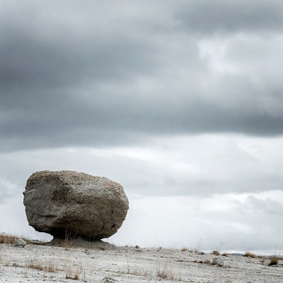 Large Boulder on Snowy Grass Under Cloudy Sky