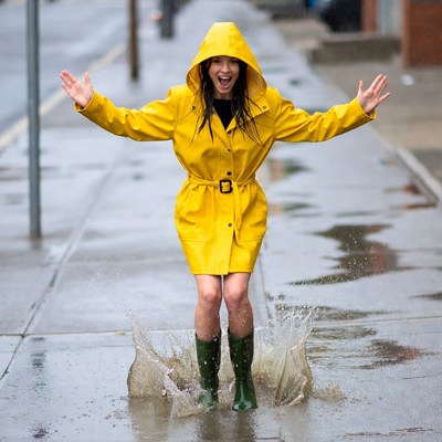 Woman jumping in puddle wearing yellow raincoat