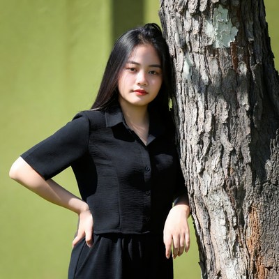 Asian woman leaning against tree