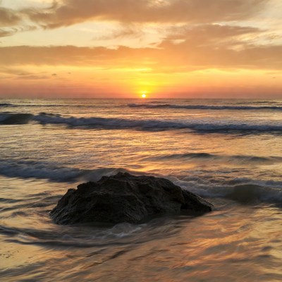 Sunset over ocean waves and rock