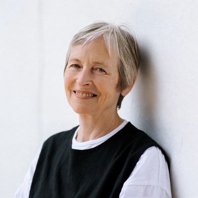 Smiling elderly woman against white wall
