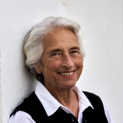 Elderly woman smiling against white wall