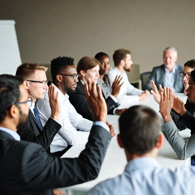 Diverse group raising hands in meeting
