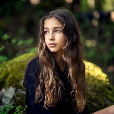 Girl sitting on mossy rock in forest