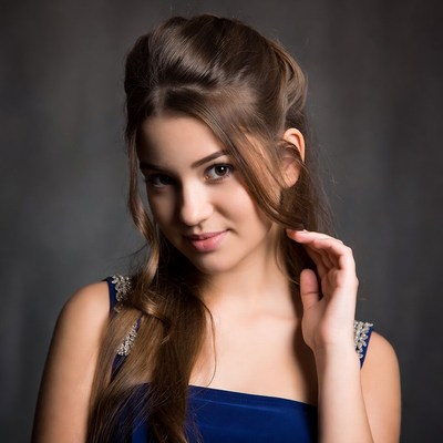 Young woman touching hair in blue dress