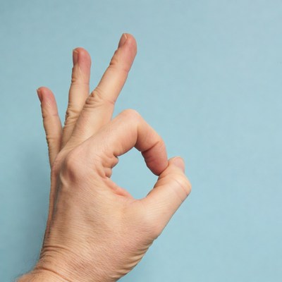 OK hand gesture on blue background