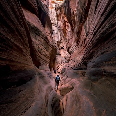 Hiker in narrow red rock slot canyon
