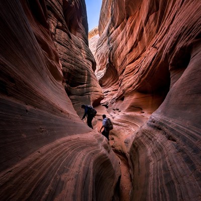 Two hikers in narrow red rock slot canyon
