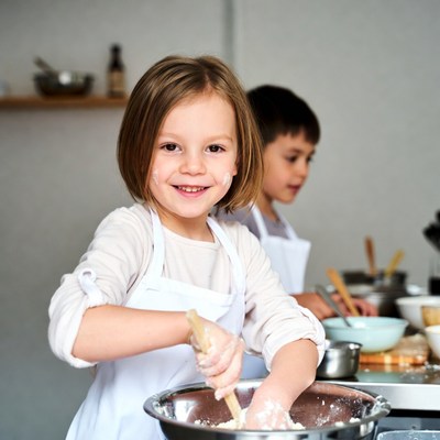 Girl mixing batter in kitchen with boy