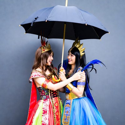 Two Asian women sharing black umbrella