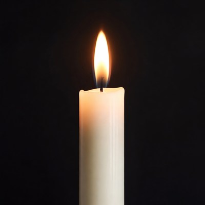 Burning white candle on black background