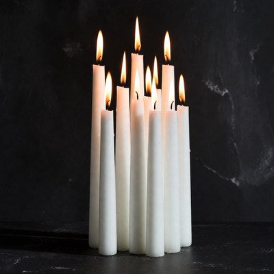 White candles burning on black background