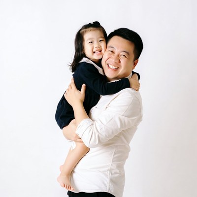 Asian father holding smiling daughter
