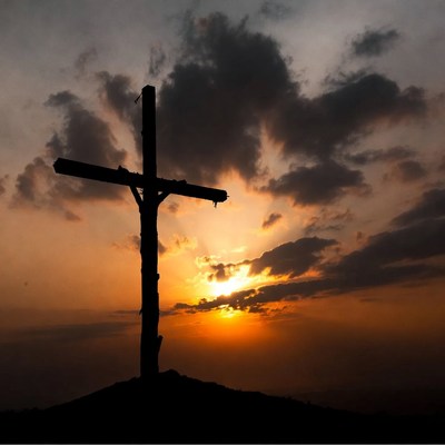Silhouette cross on hill at sunset