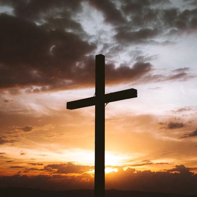 Silhouette cross against sunset sky