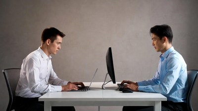 Two Asian men working on computers