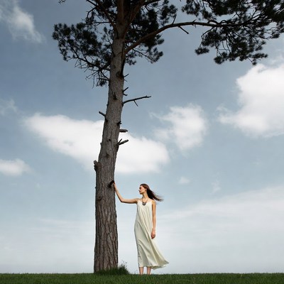 Woman touching tall pine tree