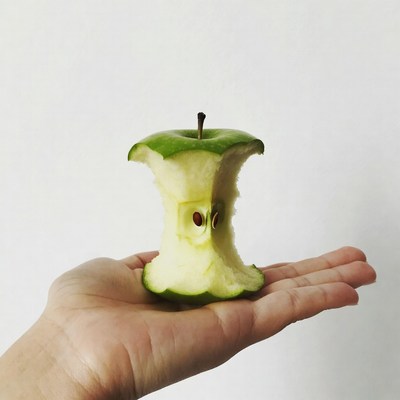 Hand holding bitten green apple