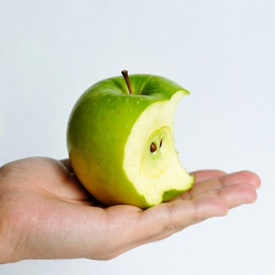 Hand holding bitten green apple