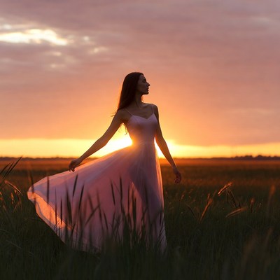 Woman in pink dress in sunset field